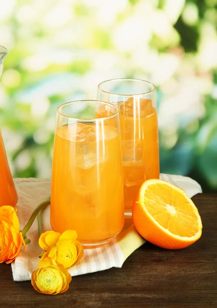 Vasos de jugo de naranja sobre mesa de madera, sobre fondo verde — Foto de Stock