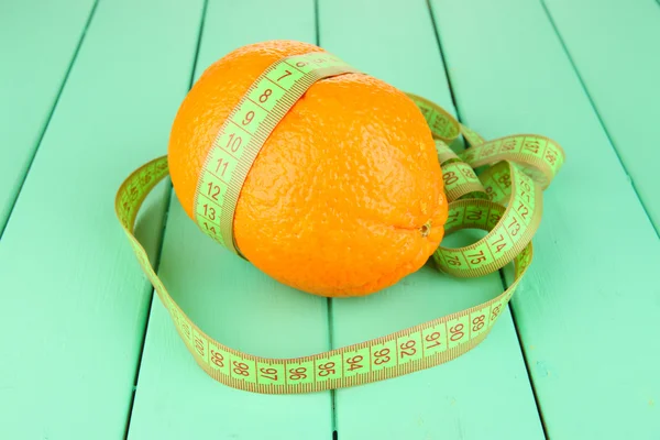 Oranje met meetlint, op een houten achtergrond kleur — Stockfoto