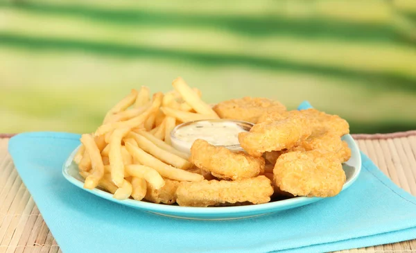 Fried chicken nuggets with french fries and sauce on table in park — Stock Photo, Image