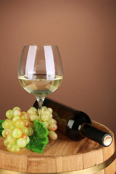 Composición de botella de vino, copa de vino blanco, uva sobre barril de madera, sobre fondo de color — Foto de Stock