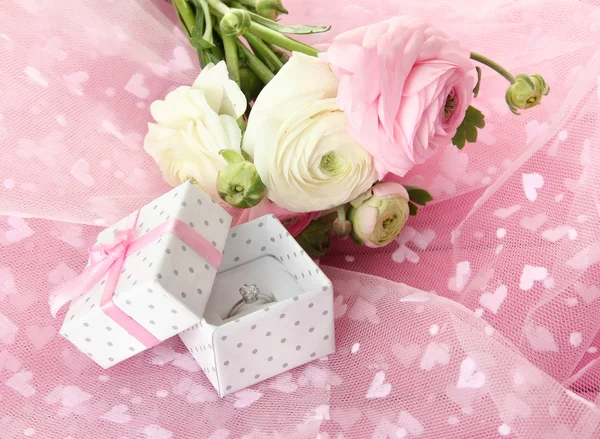 Ranunculus (persian buttercups) and engagement ring, on pink cloth — Stock Photo, Image