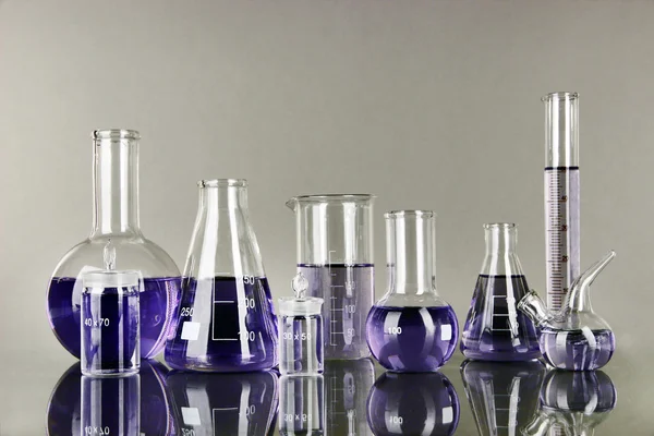 Test-tubes with light purple liquid on gray background — Stock Photo, Image