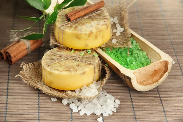 Hand-made soap and sea salt on grey bamboo mat — Stock Photo, Image