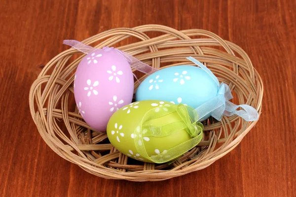 Barevné velikonoční vejce v košíku na dřevěném pozadí — Stock fotografie