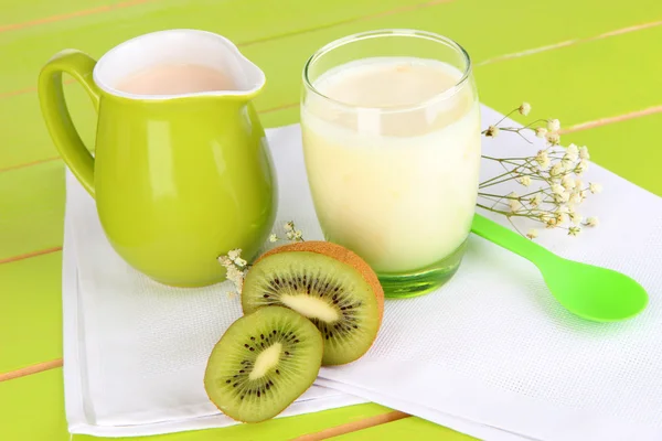 Yogurt lezat dengan kiwi dalam kaca di atas meja kayu pada latar belakang alam — Stok Foto