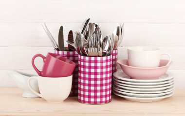 Cups, bowls nd other utensils in metal containers isolated on light background