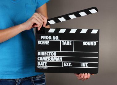 Film üretim clapper panosundaki gri arka plan üzerinde eller