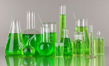 gri zemin üzerine yeşil sıvı ile test tüpleri