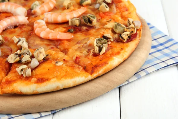 Delicious pizza with seafood on stand on wooden background — Stock Photo, Image