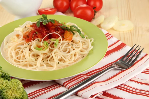 Espaguete saboroso com molho e legumes na placa na mesa de madeira close-up — Fotografia de Stock