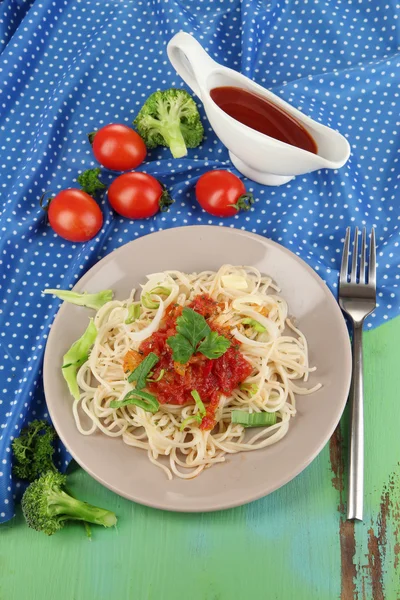 Spaghetti saporiti con salsa e verdure su piatto su tavolo di legno primo piano — Foto Stock