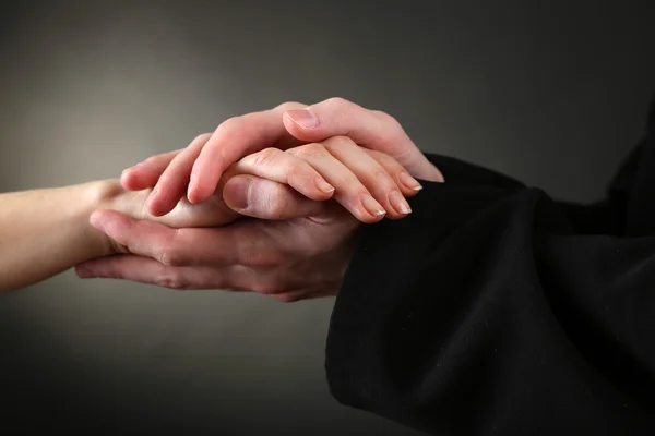 Sacerdote sosteniendo la mano de mujer, sobre fondo negro —  Fotos de Stock