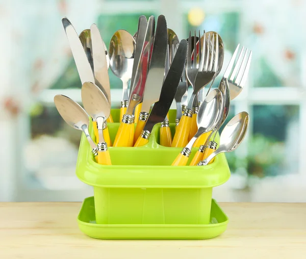 Coltelli, cucchiai, forchette in contenitore di plastica per l'essiccazione, su fondo luminoso — Foto Stock