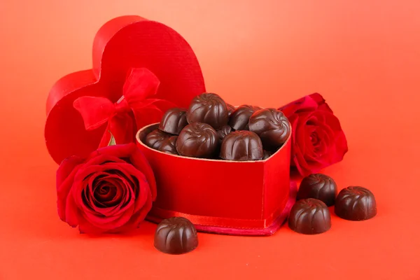 Καραμέλες από σοκολάτα σε συσκευασία δώρου, σε κόκκινο φόντο — Φωτογραφία Αρχείου