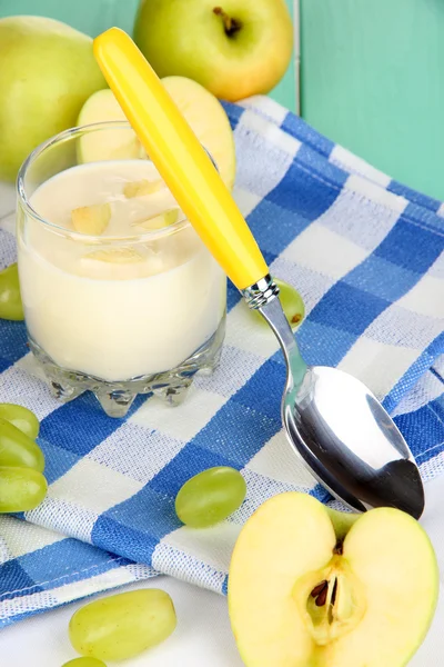 Вкусный йогурт в стакане с фруктами на деревянном столе крупным планом — стоковое фото