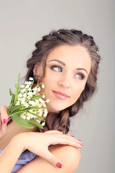 美しいヘアスタイルと灰色の背景上の花を持つ若い女性 — ストック写真