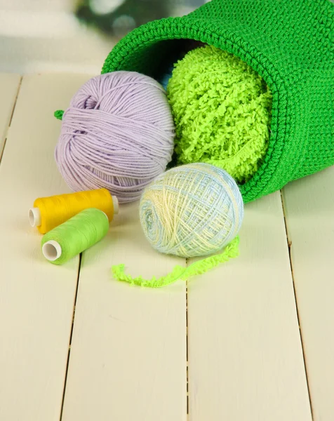 Barevné příze pro pletení v zelené koše na dřevěný stůl na pozadí okna — Stock fotografie