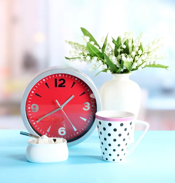 Cup tea and clock on bright background — Stock Photo, Image