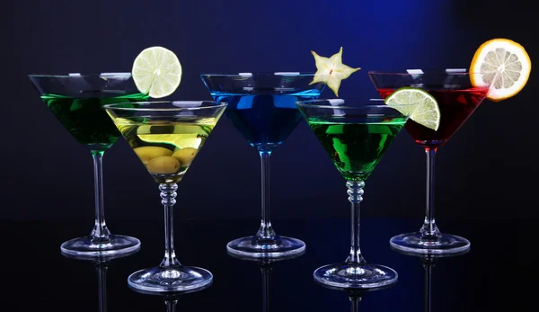 Coquetéis alcoólicos em copos de martini no fundo azul escuro — Fotografia de Stock