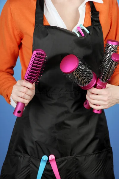 Cabeleireiro em uniforme com ferramentas de trabalho, em fundo de cor — Fotografia de Stock