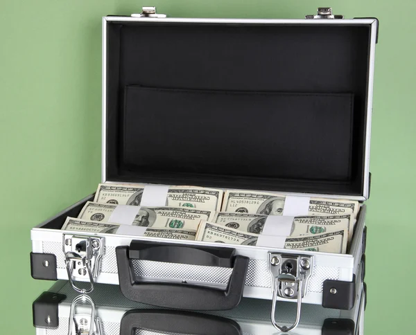 Suitcase with 100 dollar bills on green background — Stok fotoğraf