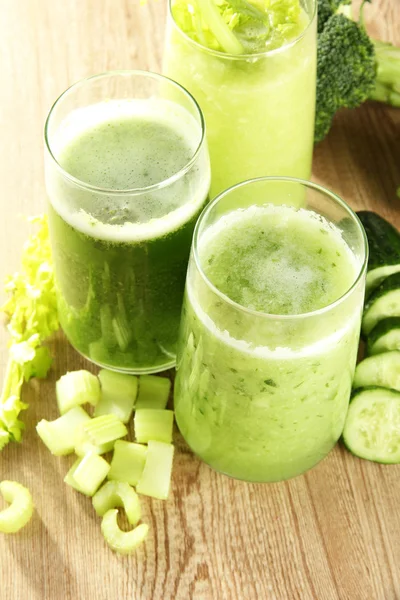 Verres de jus de légumes verts sur fond en bois — Photo