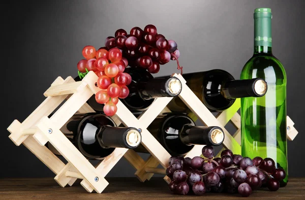 Botellas de vino colocadas sobre soporte de madera sobre fondo gris — Foto de Stock