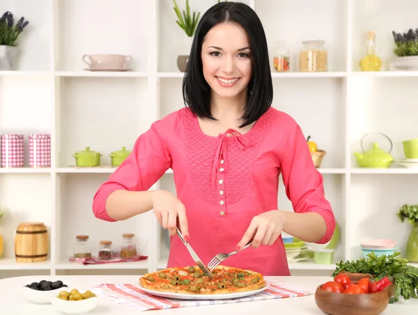 Vacker flicka vill äta läckra pizza på kök bakgrund — Stockfoto