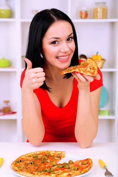 Meisje met heerlijke pizza op keuken achtergrond — Stockfoto
