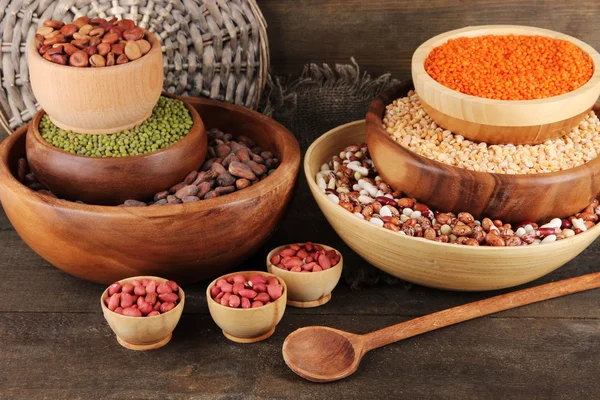 Different kinds of beans in bowls on wooden background — Stock Photo, Image