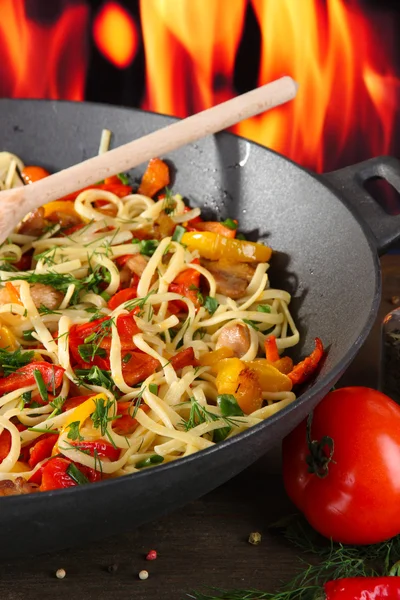 Nudlar med grönsaker på wok på brand bakgrund — Stockfoto