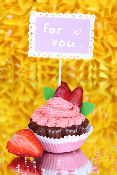 Beautiful strawberry cupcake with postcard on decorative yellow background — Stock Photo, Image