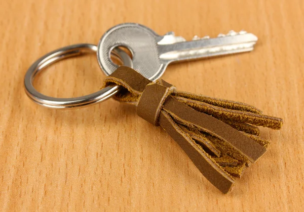 Nyckel med läder prydnadssak på trä bakgrund — Stockfoto