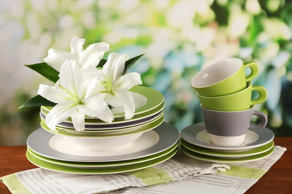 Assiettes et tasses vides sur table en bois sur fond vert — Photo