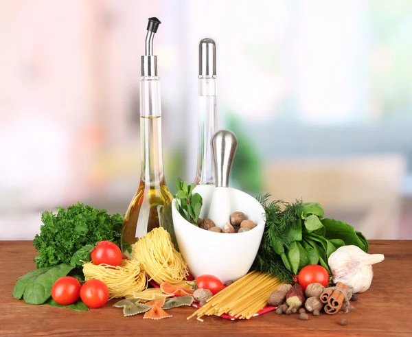 Composition of mortar, pasta and green herbals, on bright background — Stock Photo, Image