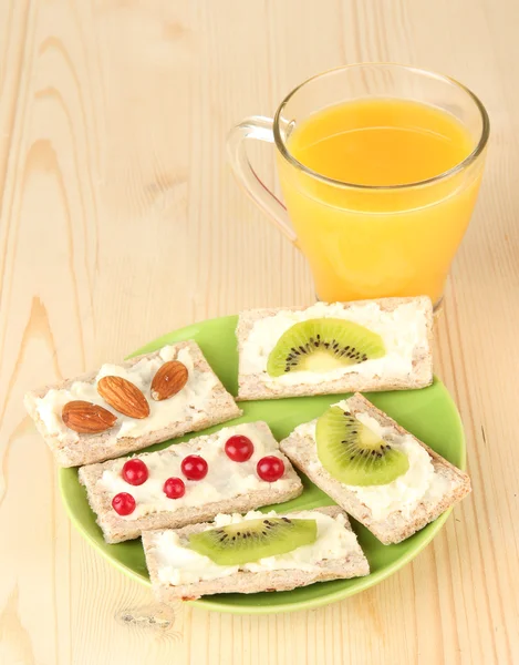 Läckra tilltugg med ost, kiwi och tranbär, mandel, på färgplåt, på trä bakgrund — Stockfoto
