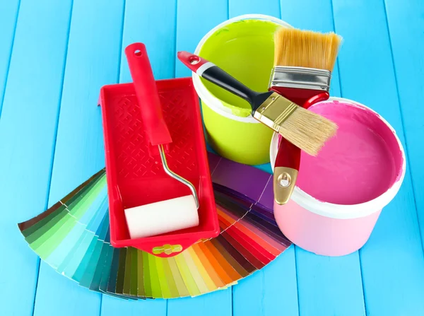 Set for painting: paint pots, brushes, paint-roller on blue wooden table — Stock Photo, Image