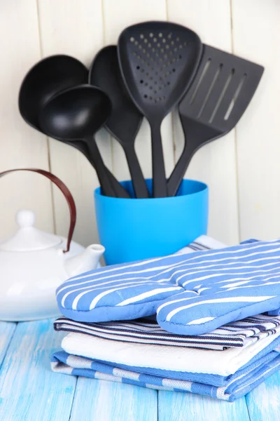 Kitchen settings: utensil, potholders, towels and else on wooden table — Stock Photo, Image