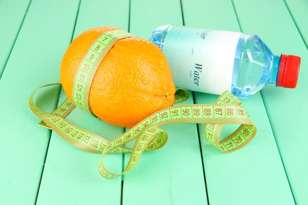Oranje met meetlint, fles water, op houten achtergrond — Stockfoto