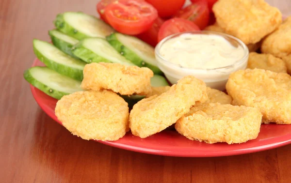 Fried chicken nuggets with vegetables and sauce on table — Stock Photo, Image