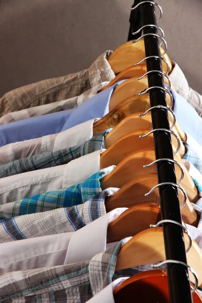 Men's shirts on hangers on gray background