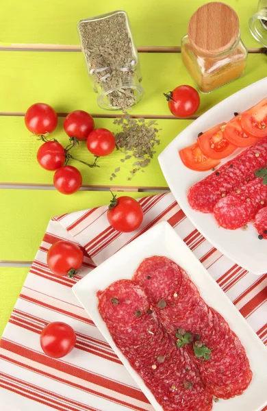 Leckere Salami auf Tellern auf Holztisch in Großaufnahme — Stockfoto