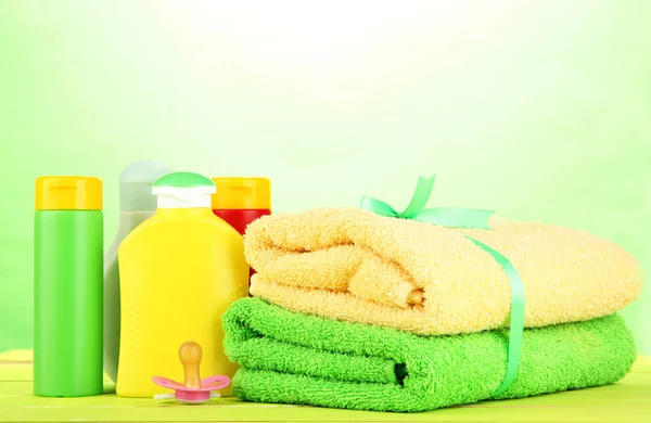 Baby cosmetica en handdoeken op houten tafel, op groene achtergrond — Stockfoto