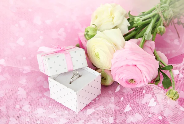 Ranunculus (persian buttercups) and engagement ring, on pink cloth — Stock Photo, Image