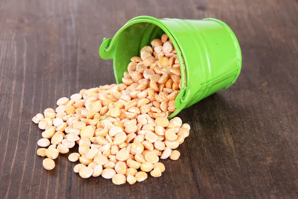 Overturned bucket with grains on wooden background — Stock Photo, Image