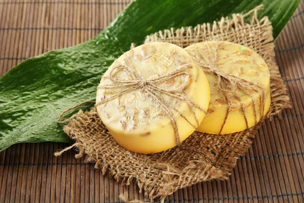 Handgemachte Seife und Blatt auf grauer Bambusmatte — Stockfoto