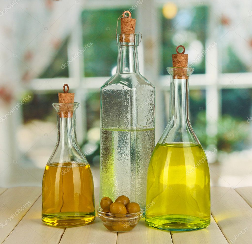 Original glass bottles with salad dressing on wooden table on window