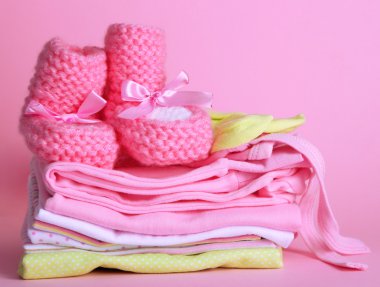 pembe bir arka plan üzerinde bebek elbise yığını