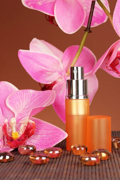 Perfume de mujer en hermosa botella con orquídeas sobre fondo marrón — Foto de Stock