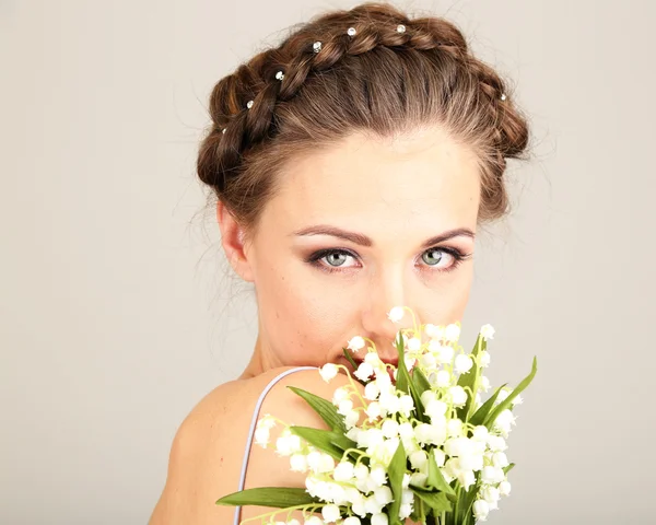 Güzel saç modeli ve gri arka plan üzerinde çiçekler olan kadın — Stok fotoğraf